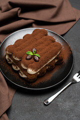 Classic tiramisu dessert on ceramic plate on concrete background