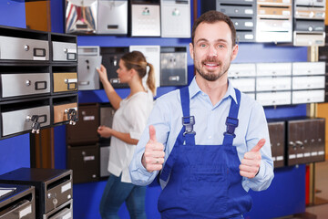 Obraz premium Confident seller male in blue overall standing in mailbox store