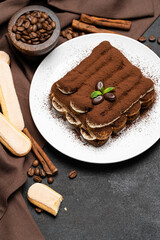 Classic tiramisu dessert on ceramic plate and savoiardi cookies on concrete background