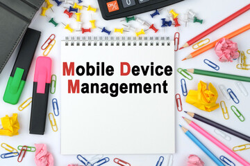 On the table is a calculator, diary, markers, pencils and a notebook with the inscription - Mobile Device Management