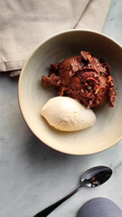 Top-down view flat lay style of a bowl with chocolate pudding and vanilla ice cream at a luxury restaurant table
