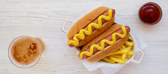 Homemade Mustard Hot Dog with French Fries and Glass of cold Beer on a white wooden surface, top...