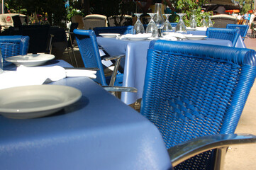 Blue chairs at a bright outdoor dining restaurant with white table setting