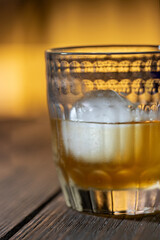 Whiskey with ice in glasses onn wooden background. Close up