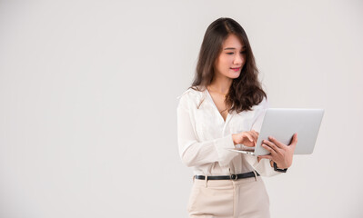 A happy Asian business woman working on a laptop computer on a white background.