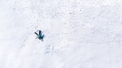 Happy girl lying on snow and making snow angel figure