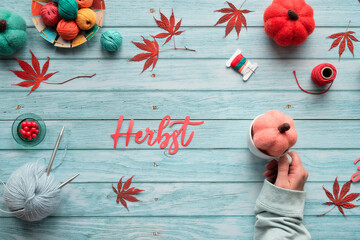 Herbst means Autumn in German. Seasonal Fall flat lay with wool bundles, yarn balls, maple leaves...