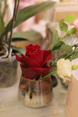 Red rose  and other flowers in small vase.