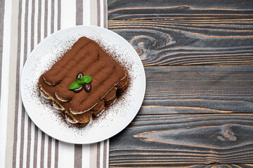 Classic tiramisu dessert on ceramic plate on wooden background