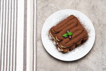 Classic tiramisu dessert on ceramic plate on concrete background