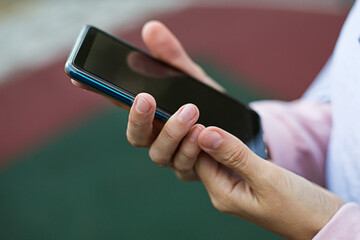 Smartphone in women's hands close-up. Using the phone, fingers on the touch screen of the gadget. Text messages, doing business, Internet applications. Space for text