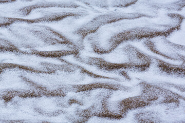 Abstract shapes with sand dunes covered by fresh powder snow, in a wild river bed, in winter