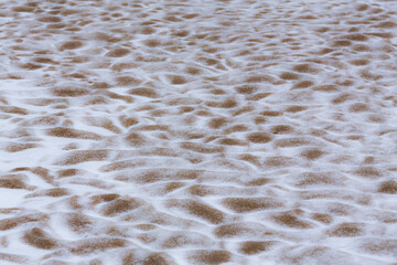 Abstract shapes with sand dunes covered by fresh powder snow, in a wild river bed, in winter