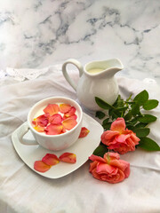 Cup of milk for a better nights sleep with rose petals on white background. Image with copy space, top view