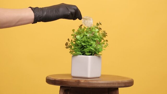 Depilation concept. Female hand in black gloves on a yellow background with shugaring paste.