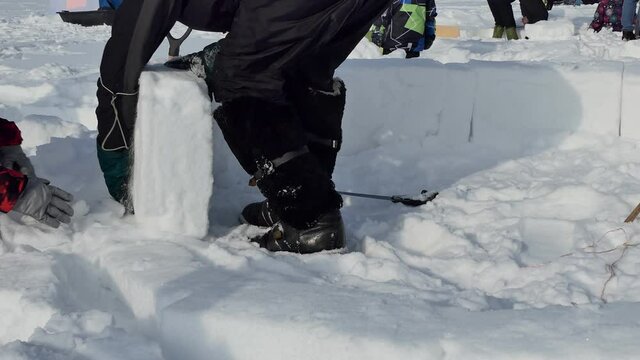 Igloo. A man cuts out a snow block with a hacksaw to build an Igloo. Close up. 