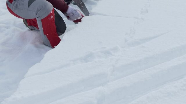 Igloo. A woman cuts out a snow block with a hacksaw to build an Igloo. Close up. 