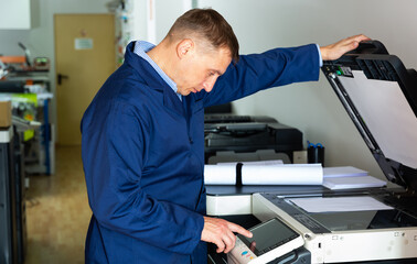 Portrait of confident service engineer standing by photocopy machine in office. High quality photo
