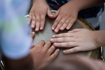 Children playing together at djembe drum, close up. Beating the djembe