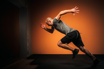 Side view of male athlete sprinting inside a gym.