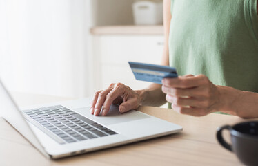 Fototapeta premium Young woman holding credit card and using laptop computer at home, Businesswoman or entrepreneur working, Online shopping, e-commerce, internet banking, spending money concept