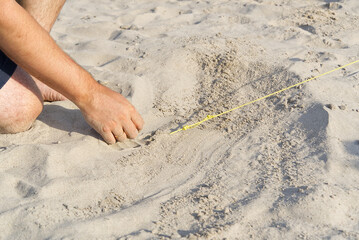 a metal peg driven into the sand to pull the rope out of the tent. Camping on a sandy beach. man raises a tent on the beach. nature travel concept.