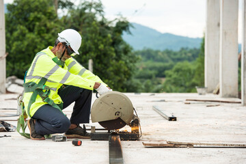 A construction worker with a steel grinder is cutting a brightly lit steel pipe.