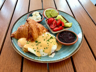 Breakfast Plate with Croissant Poached Egg Benedict and Hollandaise Sauce at Cafe Restaurant.