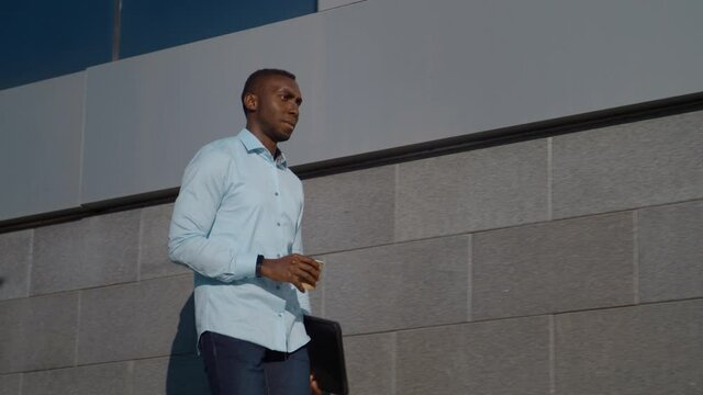 Successful African American business man walks down the street near a business office