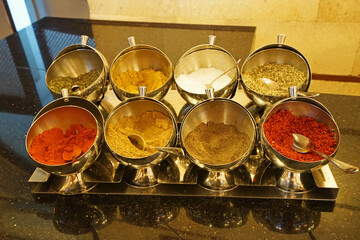 Assorted seasoning and powder station- sugar, salt, garlic, ground saffron, chili, pepper and curry spices