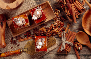 Layered cakes with cinnamon, anise, coffee beans and nuts on a old wooden table.