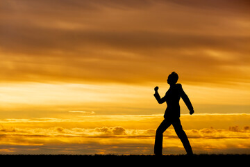 夕陽を背景に元気よく歩く男性のシルエット