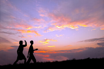 Fototapeta na wymiar 夕陽を背景に元気よく歩く男女高校生のシルエット