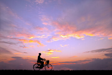 Fototapeta na wymiar 夕陽を背景に自転車通学する男子高校生のシルエット