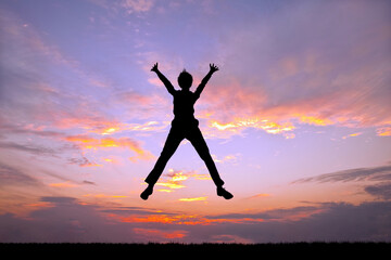 夕陽を背景に元気よくジャンプする男性のシルエット
