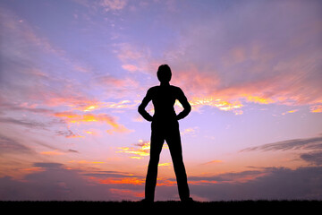 夕陽を背景に腰に手を当て立ち姿の男性のシルエット