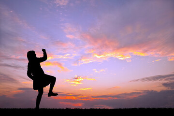 夕陽を背景に元気よく歩く女性のシルエット