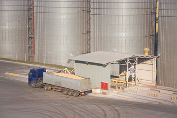 A truck with a full body of grain stands next to a truck unloading station at a grain terminal
