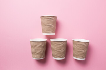 Paper cup for hot coffee or tea on a pink isolated background.