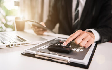 Businessman working on desk office with using a calculator to calculate the numbers, finance concept in office.