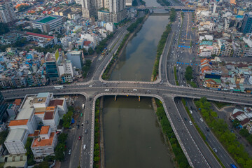 Symmetrical drone view of Ben Nghe canal featuring Saigon, Vietnam City skyline Ong Lanh and Calmette bridges and foggy morning day time traffic