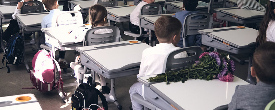 Moderd school smart classroom with young student. View of elementary class room with chairs and deskd tables in campus. Primary school backpacks.