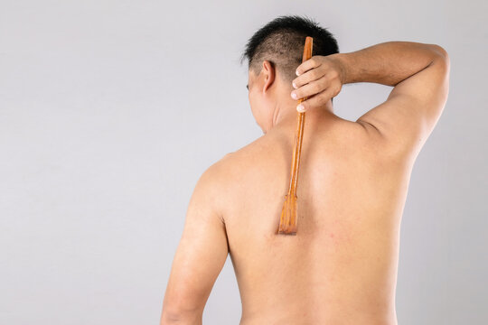 Health care or Itchy or Tinea Cruris concept : Portrait of people using Scratch wood stick to Scratching on his back side. Studio shot on grey