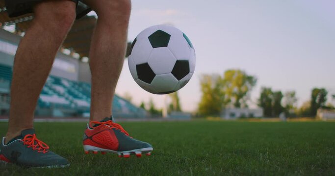 Tilt up with slow motion of male from professional soccer league juggling ball on leg in outdoor playing field on sunny summer day