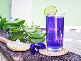 Fototapeta na wymiar Fresh purple Butterfly pea or blue pea flower and juice in glass with lime on wooden table. 