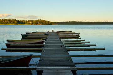 Fototapeta premium Boats moored on the mole of the tranquil lake on a sunset.