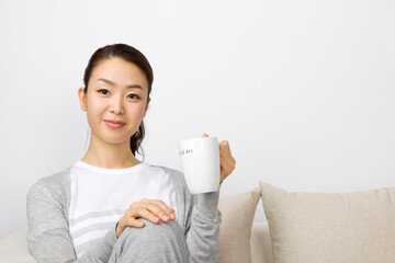 young woman having a tea sitting on sofa