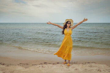 Fototapeta na wymiar freedom woman with arms raised on sea beach with wind blow