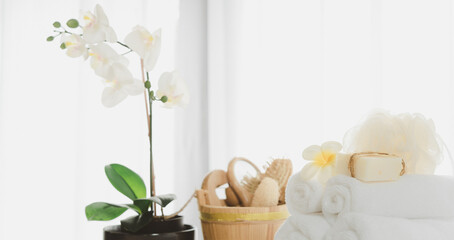 Spa products with white towels,soap,luffa scrub,comb and beautiful orchid flower in clean white room