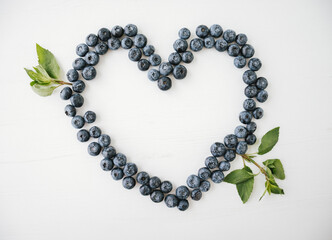 Love heart shape made of blueberries on bright background.